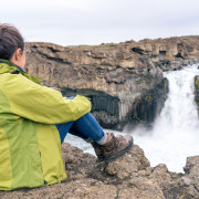 Female hiker looking at Aldeyjarfoss waterfall, Iceland.